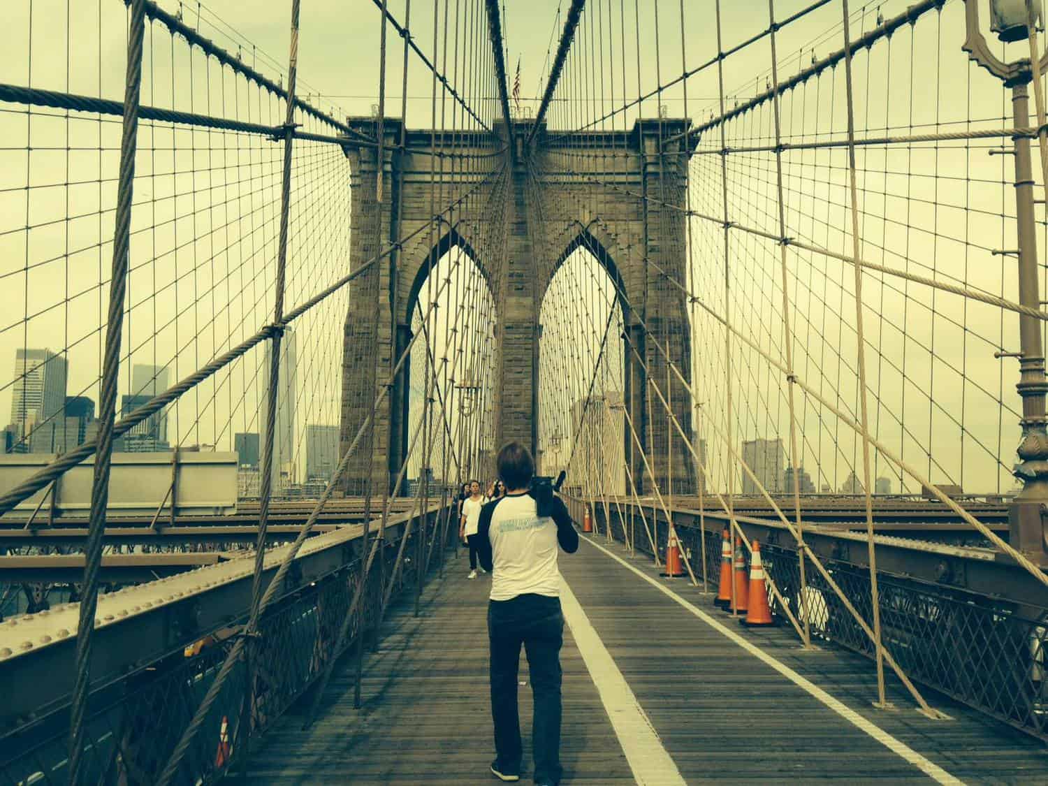 A man films people walking on a bridge