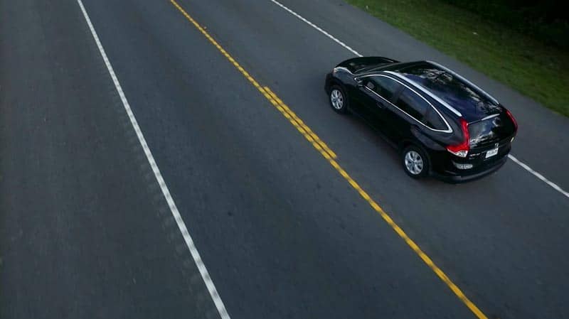 A black Honda SUV drives on the right side of the road