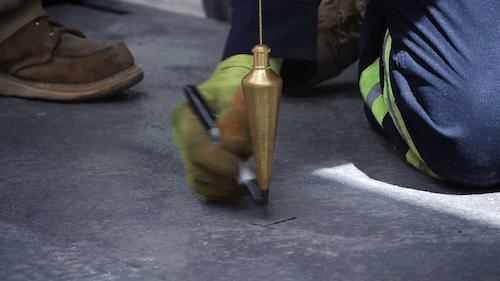 Construction worker outlines hole for drill on cement block