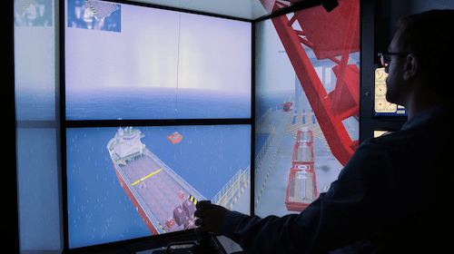 A man prepares to drop supplies form a crane onto a boat deck from a computer