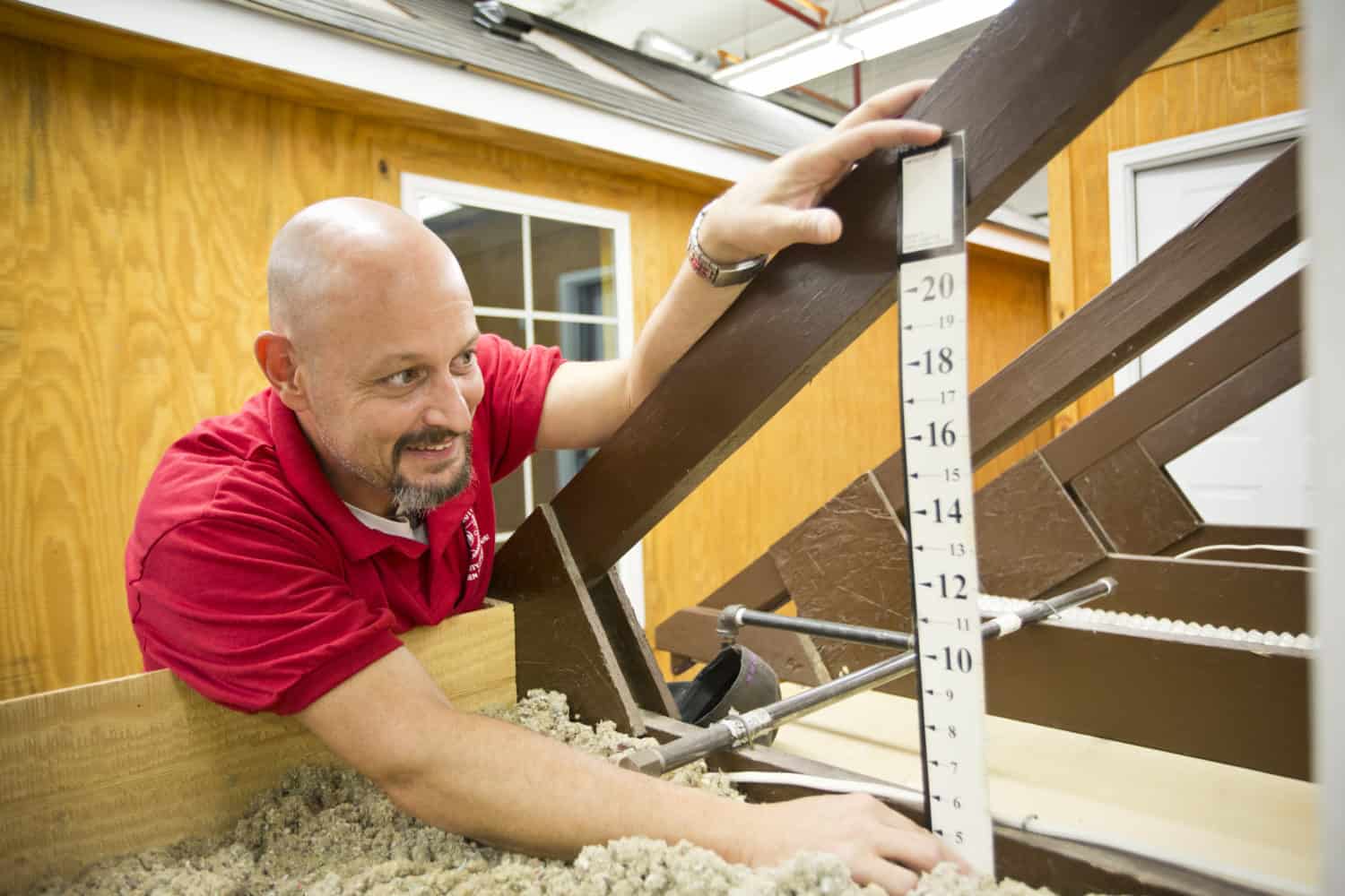 An attic sealing professional measures a model attic frame angle