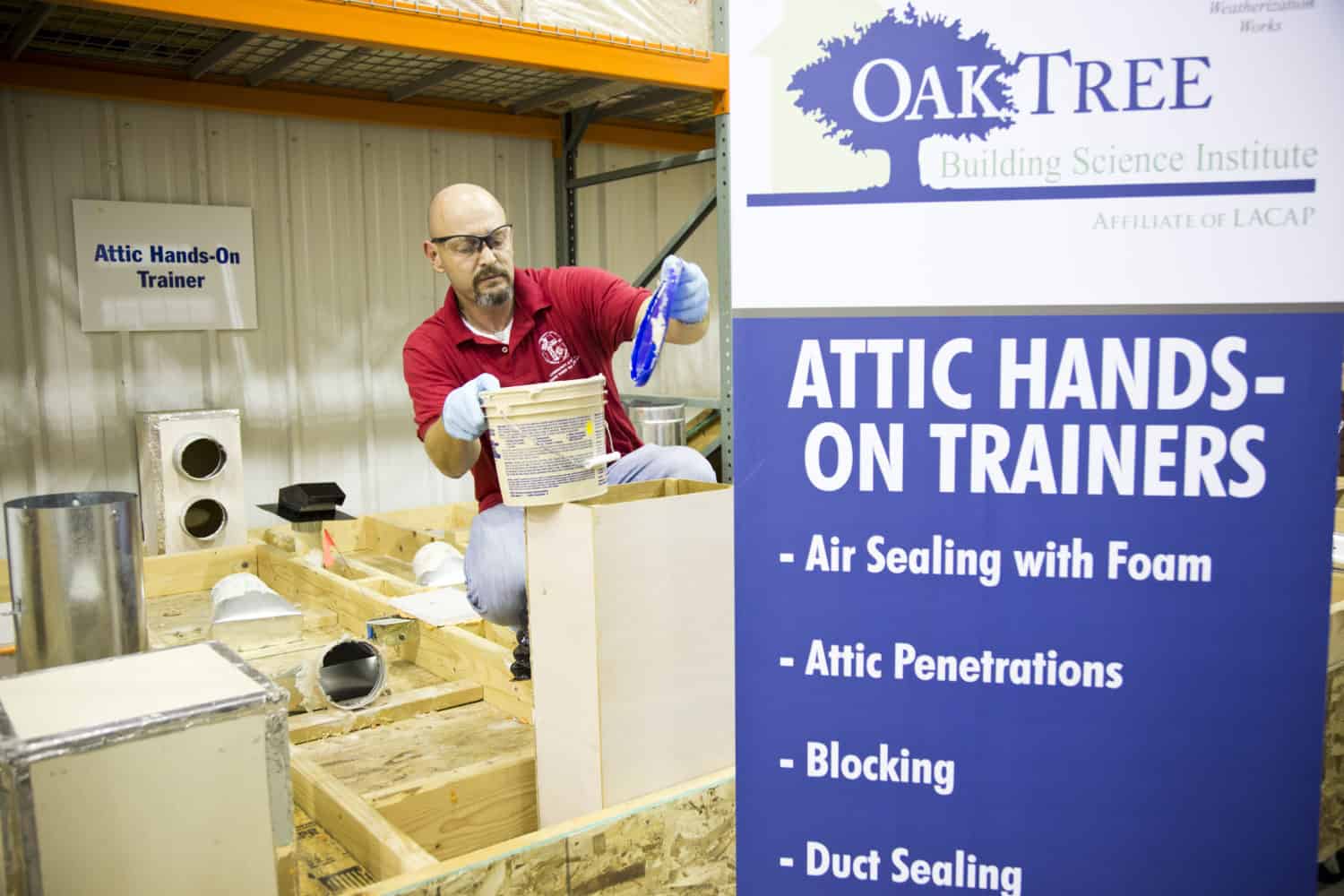 An attic hand-on trainer performs a demonstration with air sealing foam