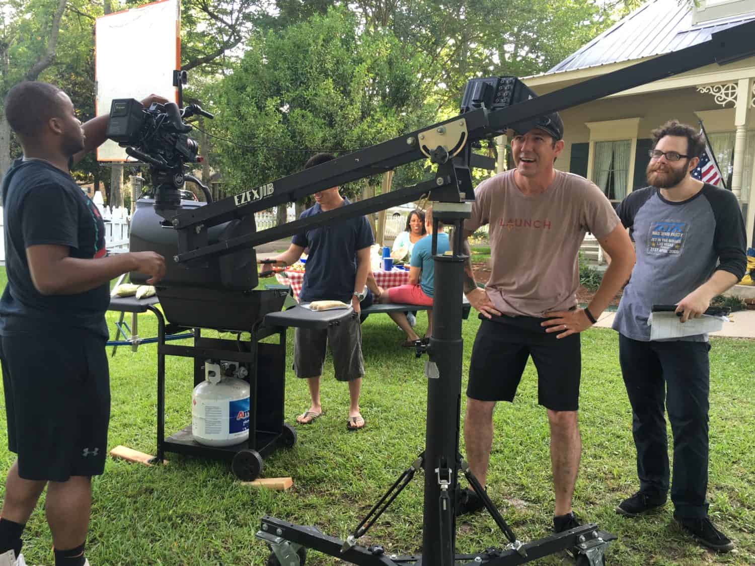 Three camera men stand around production equipment at a picnic film set