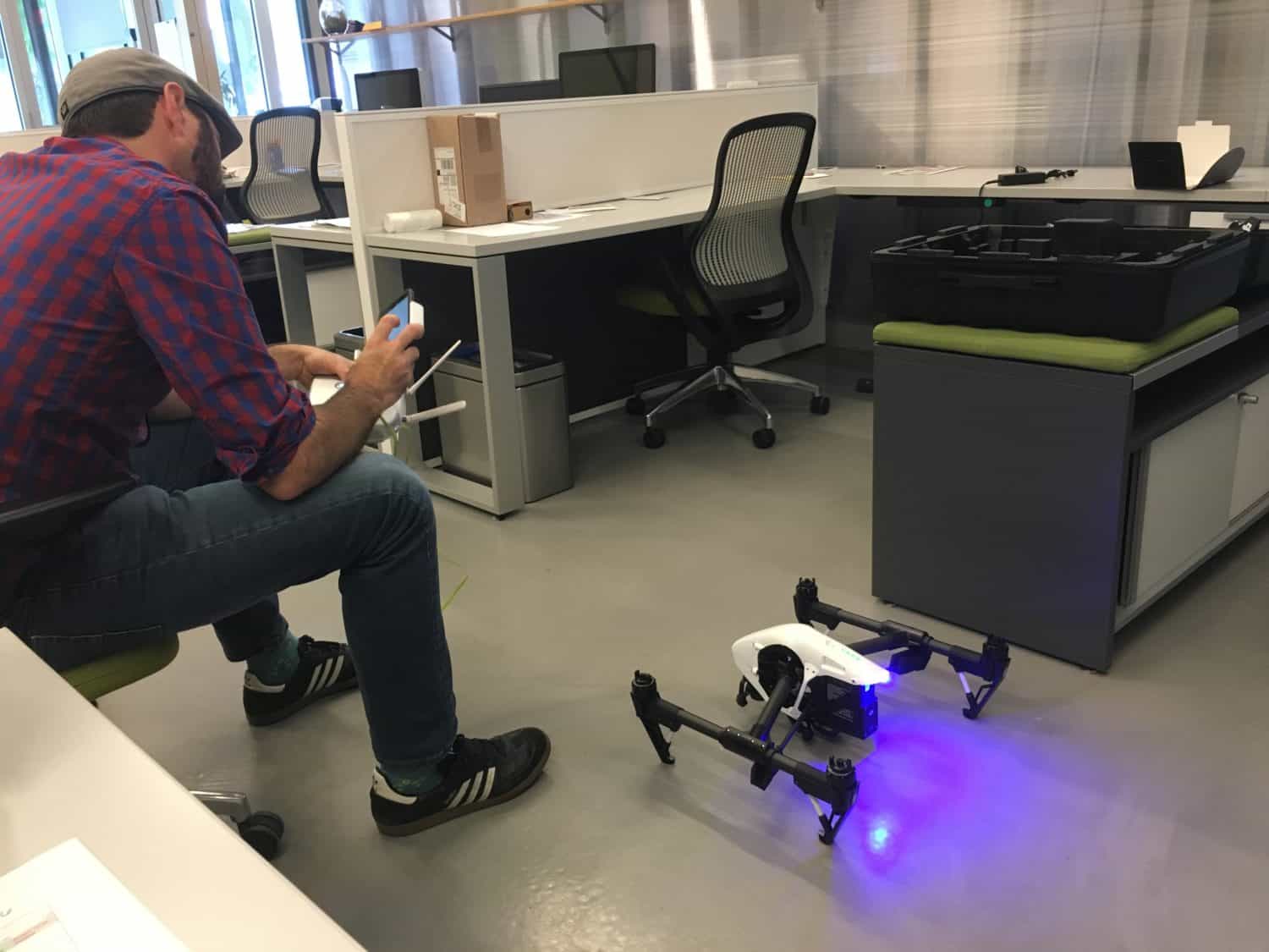 A man in plaid shirt plays with a drone in the Creative Bloc office