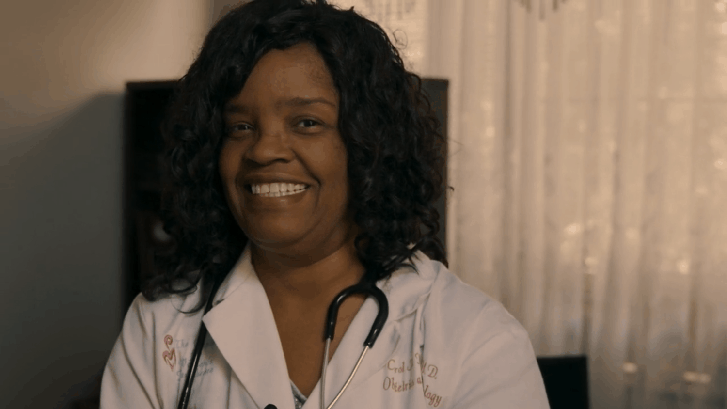 An African-American woman doctor smiles in her office